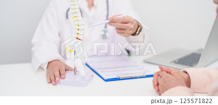 Elderly Patient consulting Doctor with Spine anatomy for Spinal Cord Disorder and disease, Back pain, Lumbar, Sacral pelvis, Cervical neck, Thoracic, Coccyx, Orthopedist, chiropractic, Office Syndrome 125571822