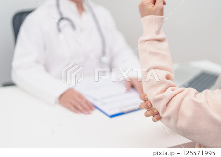 Elderly Woman having elbow ache and consulting doctor in hospital. muscle pain due to lateral epicondylitis or tennis elbow. injury, Health and medical consultation concept 125571995