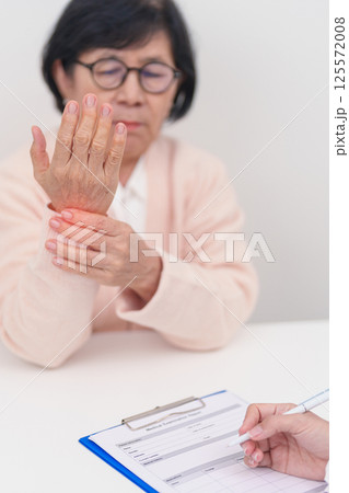 Elderly Patient Woman wrist pain and Consulting doctor. muscle ache from Carpal Tunnel Syndrome, De Quervain s tenosynovitis, rheumatoid, arthritis, gout, Parkinson disease and ergonomic healthcare 125572008