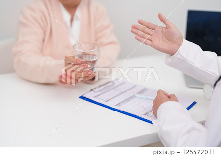 Senior woman with Tremor hand during taking glass of water in hospital. Parkinson disease April awareness month, Carpal Tunnel Syndrome, rheumatoid and brain injury and Neurological disorder concept 125572011