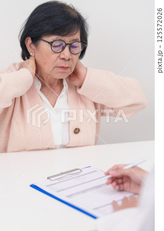 Elderly Woman having Shoulder and Neck and consulting doctor in hospital. Muscle painful due to Myofascial pain syndrome and Fibromyalgia, rheumatism, Scapular pain, Cervical Spine. ergonomic concept 125572026