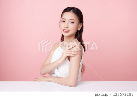 A beautiful young Asian woman with clean, fresh skin against a pink background. Skincare, facial treatment, cosmetology, beauty, and spa. An elegant portrait of an Asian woman. A beautiful young Asian woman with clean, fresh skin against a pink background. Skincare, facial treatment, cosmetology, beauty, and spa. An elegant portrait of an Asian woman. 125572185