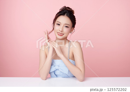 A beautiful young Asian woman with clean, fresh skin against a pink background. Skincare, facial treatment, cosmetology, beauty, and spa. An elegant portrait of an Asian woman. 125572202