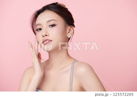 A beautiful young Asian woman with clean, fresh skin against a pink background. Skincare, facial treatment, cosmetology, beauty, and spa. An elegant portrait of an Asian woman. 125572205