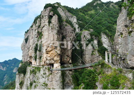 a suspension bridge on the edge of a cliff in the mountains, Zhejiang Province, China 125572435