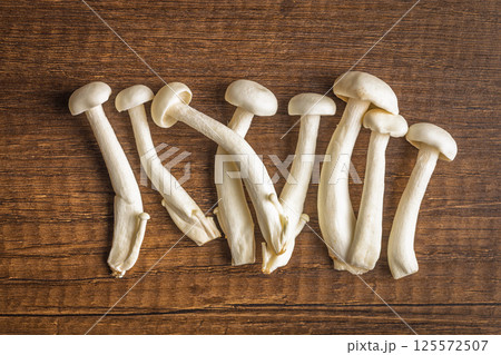 Raw white shimeji mushrooms on wooden table. Top view. Raw white shimeji mushrooms on wooden table. Top view. 125572507