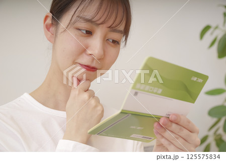 通帳を見て複雑な表情をする女性 125575834