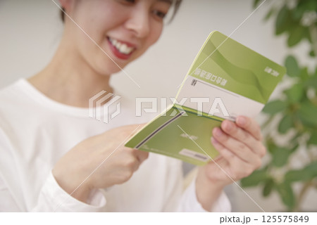 通帳を見てほほえむ女性 通帳を見てほほえむ女性 125575849