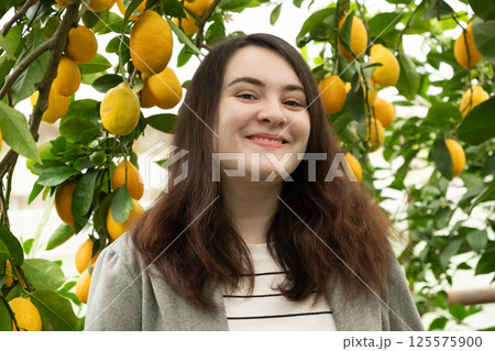 Woman in lemon orchard smiling and looking at camera Woman in lemon orchard smiling and looking at camera 125575900