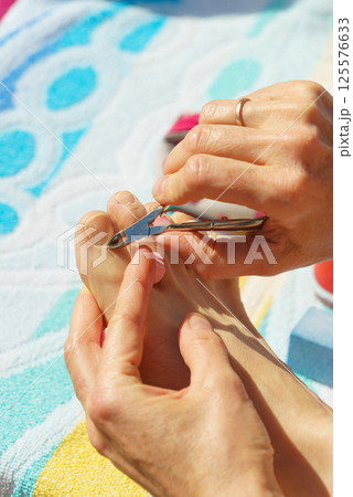 Woman trimming cuticles before pedicure Woman trimming cuticles before pedicure 125576633