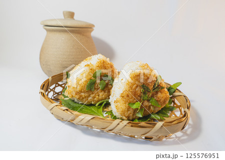 白を背景にザルの上にのった山椒とゴマの味噌焼きおにぎりと味噌壺の写真 125576951
