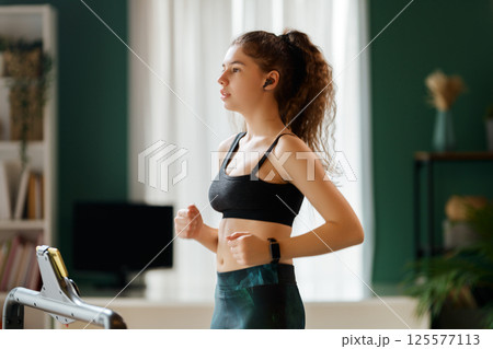 Young woman running on a treadmill indoors 125577113