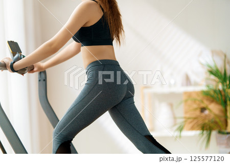 Young woman running on a treadmill indoors 125577120