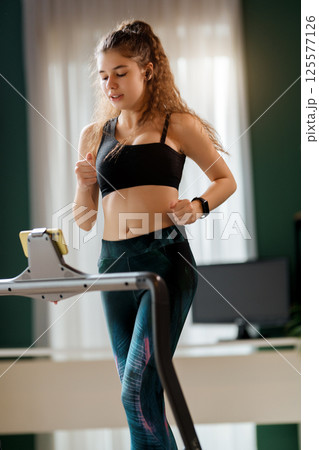 Young woman running on a treadmill indoors Young woman running on a treadmill indoors 125577126