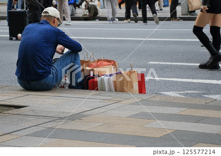 歩行者天国で歩道に座って休む買い物客 歩行者天国で歩道に座って休む買い物客 125577214