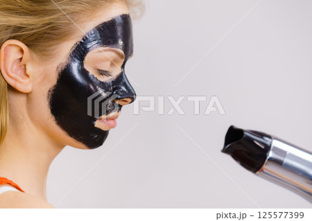Girl drying peel-off black mask on face 125577399