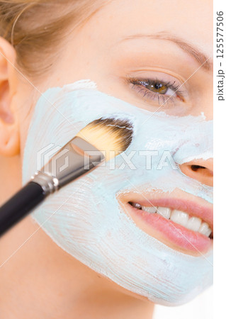 Girl apply green mud mask to face 125577506