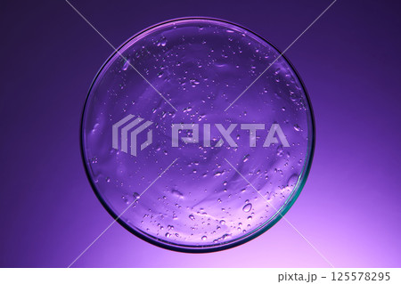 Top view of clear thick liquid with molecular bubbles stuck together. Petri dishes with cosmetic smudge and drops presented on purple fluid. Science cosmetic laboratory concept. Flat lay. Top view of clear thick liquid with molecular bubbles stuck together. Petri dishes with cosmetic smudge and drops presented on purple fluid. Science cosmetic laboratory concept. Flat lay. 125578295