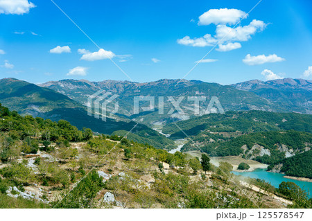 Wide angle view of a mountainous landscape with a big blue sky and some clouds near Tirana in Albania 125578547
