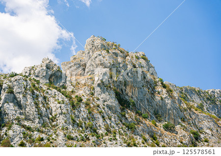 Large rocky mountain in the sun under a blue sky Large rocky mountain in the sun under a blue sky 125578561