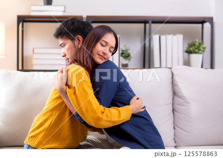 Young asian couple hug sitting on sofa with affectionate in living room at home. Young asian couple hug sitting on sofa with affectionate in living room at home. 125578863