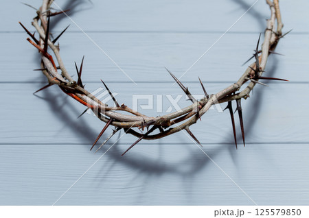 Wooden wall casting dark shadow from Jesus crown of thorns, symbolizing religious suffering and sacrifice Christian background Easter concept 125579850