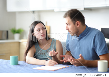 Angry asian woman asking her confused partner about document 125580471