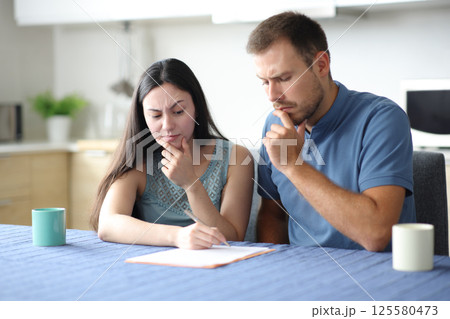 Suspicious interracial couple or roommates checking document Suspicious interracial couple or roommates checking document 125580473