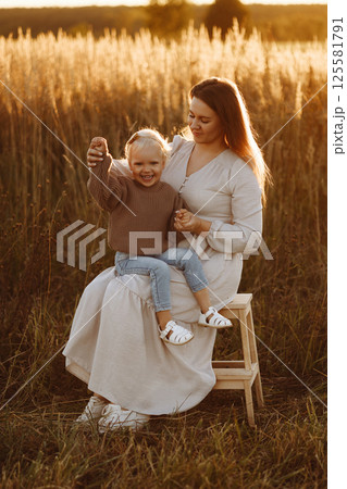 Mother and Daughter Smiling in Wheat Field at Sunset 125581791