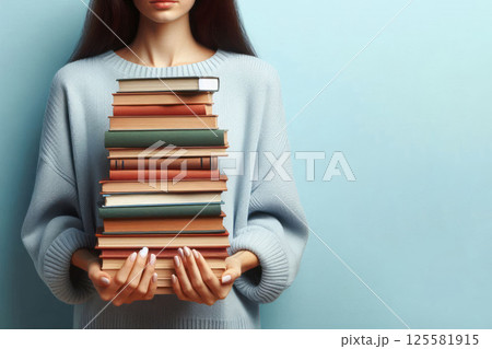 A girl with a large stack of books in her hands. Space for text. 125581915