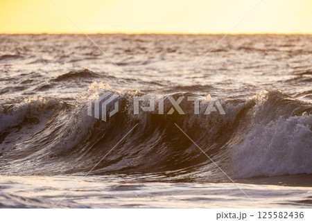 Golden Sunset Waves Gracefully Crashing onto the Shore with Beauty and Tranquility Golden Sunset Waves Gracefully Crashing onto the Shore with Beauty and Tranquility 125582436