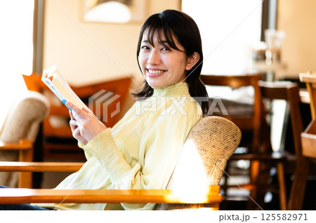 ソファでくつろぎながら本を読む若い女性 125582971