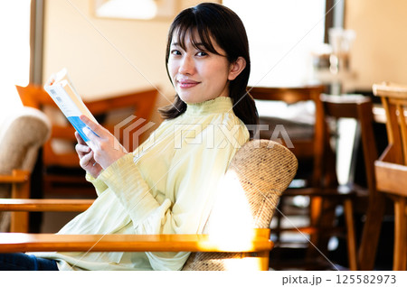 ソファでくつろぎながら本を読む若い女性 ソファでくつろぎながら本を読む若い女性 125582973