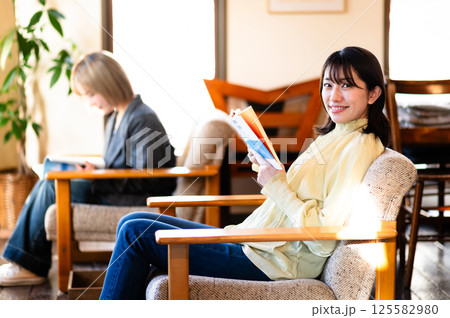 ソファでくつろぎながら本を読む若い女性 ソファでくつろぎながら本を読む若い女性 125582980