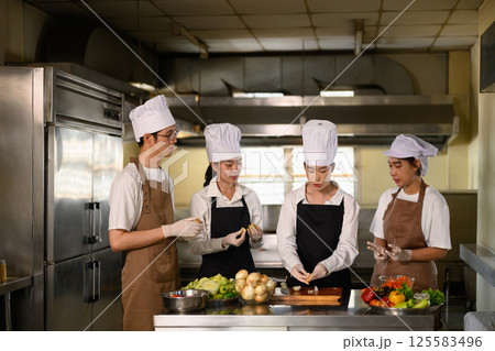 Cooking instructor guiding students in vegetable preparation during hands on class Cooking instructor guiding students in vegetable preparation during hands on class 125583496