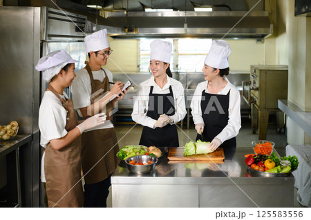 Cooking instructor guiding students in vegetable preparation during hands on class 125583556