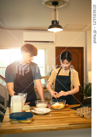 Young man and woman preparing homemade pancake in a cozy kitchen Young man and woman preparing homemade pancake in a cozy kitchen 125583610