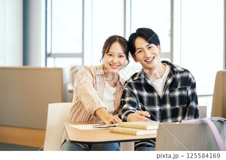 学校のフリースペースで勉強をする男女学生のポートレート 125584169