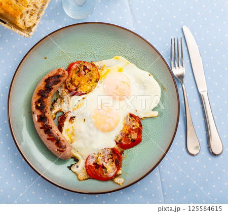 Breakfast from sunny-side-up eggs with sausages and tomatoes Breakfast from sunny-side-up eggs with sausages and tomatoes 125584615