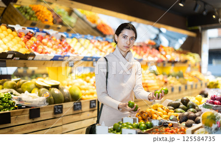 Young woman choosing lime in vegetable shop 125584735