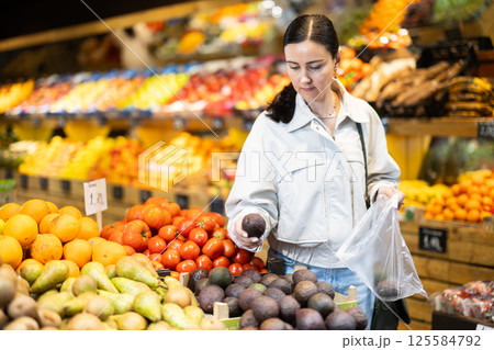 Middle-aged woman choosing avocado in grocery store 125584792