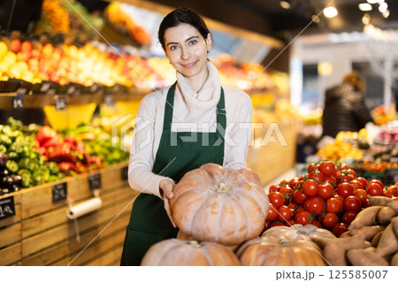 Woman seller checking pumpkin Woman seller checking pumpkin 125585007