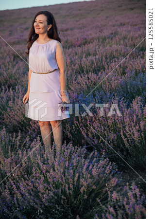 Woman in dress in lavender field before harvest 125585021