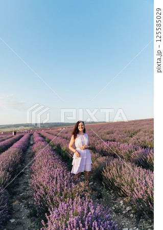 Woman in a dress walking in summer in a field of fragrant lavender Woman in a dress walking in summer in a field of fragrant lavender 125585029