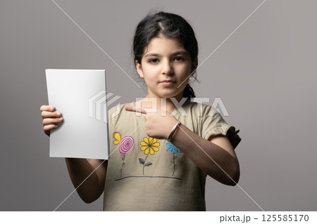 Little girl pointing a novel book with blank cover mock-up series 125585170