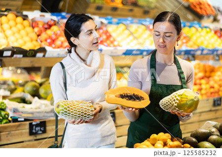 Woman consults a seller about choosing a papaya 125585232