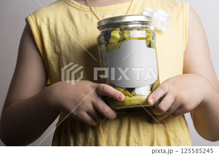 Close up shot a little girl holding a pickled okra glass conserve at hands mock-up series Close up shot a little girl holding a pickled okra glass conserve at hands mock-up series 125585245