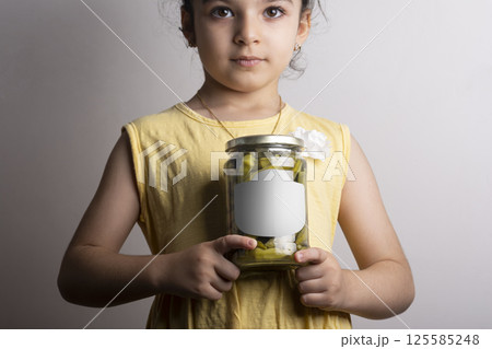 Little girl holding a pickled okra glass conserve at hands mock-up series  125585248