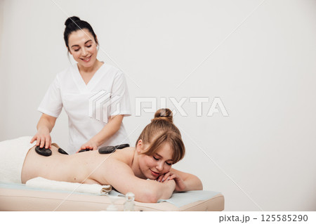 Woman on table at masseur on back massage in spa Woman on table at masseur on back massage in spa 125585290