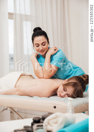 Woman on table at masseur on back massage Woman on table at masseur on back massage 125585302